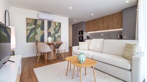 A modern living room with a white sofa, a dining table with chairs, and abstract art on the wall. - Polacos Residence | 1BR | Apt T by LovelyStay (Vila Nova de Gaia)