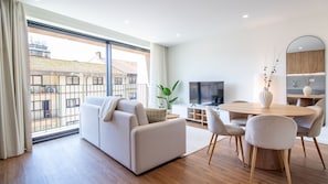 Ein modernes Wohnzimmer mit einer Couch, Fernseher, Esstisch und Stühlen.