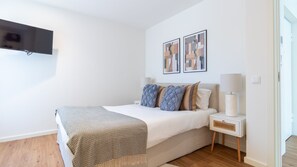 Ein Schlafzimmer mit einem Bett, Nachttischen, einer Lampe und Bildern an der Wand.