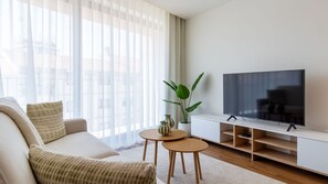 A modern living room with a sofa, a coffee table, a TV on a stand, and a potted plant. - Polacos Residence | 1BR | Apt Y by LovelyStay (Vila Nova de Gaia)