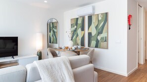 A modern living room with a flat-screen TV, a round dining table with chairs, abstract art on the walls, and a white fireplace. - Polacos Residence | 1BR | Apt Y by LovelyStay (Vila Nova de Gaia)