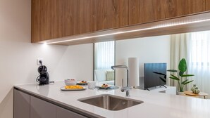 Une cuisine moderne dotée d’un évier en acier inoxydable, d’une machine à café et d’un coin repas avec une table mise pour deux personnes.
