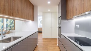Une cuisine moderne dotée d’appareils électroménagers en acier inoxydable, de meubles en bois et d’un design épuré et minimaliste.