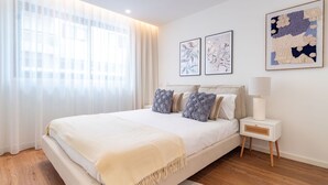 Une chambre d’hôtel avec un lit, une table de chevet, une lampe et des œuvres d’art accrochées au mur.