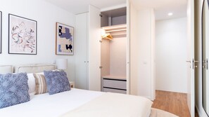 Een slaapkamer met een bed, een inloopkast en twee ingelijste kunstwerken aan de muur.