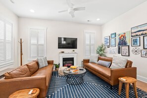 A living room with a fireplace, two sofas, a coffee table, and a TV. - Downtown Delight on Main Street - Brevard, NC (Brevard)