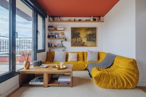Ein modernes Wohnzimmer mit einem gelben Sofa, einem Couchtisch mit Büchern und einem Gemälde an der Wand.