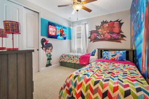 Een slaapkamer met twee bedden, een plafondventilator en wanddecoraties, waaronder een Disney-film poster.
