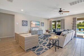 A modern living room with a sofa, two armchairs, a coffee table, and a ceiling fan. - The Encore Bliss - Nine Bedroom Apartment, Sleeps 18 (Kissimmee)