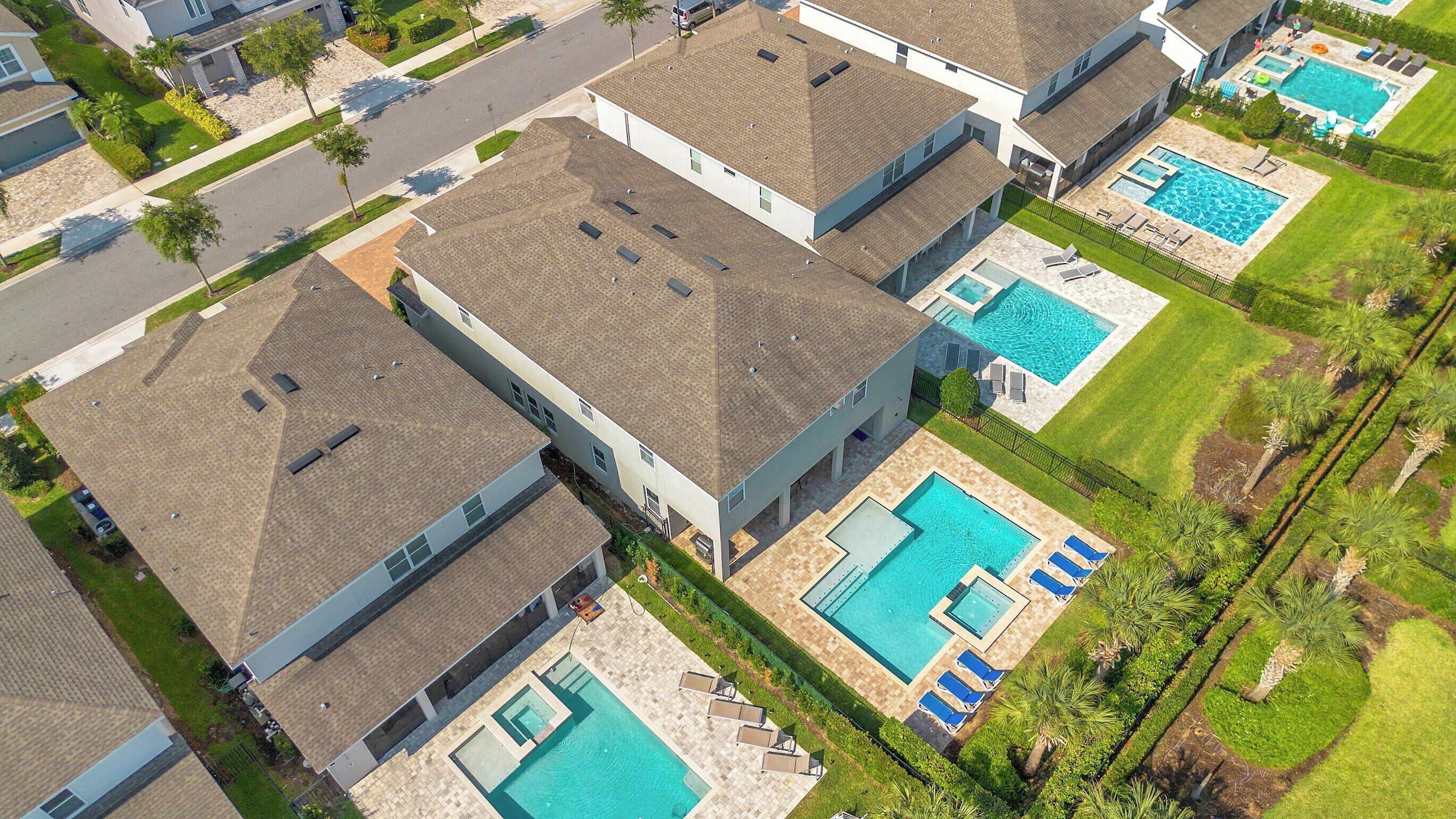 Un barrio residencial con varias casas, cada una con piscina y césped cuidado.