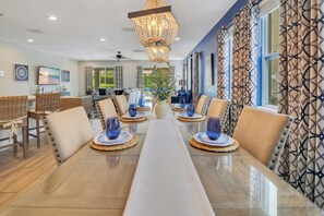 A dining area with a long table, chairs, and a chandelier. - The Encore Bliss -  Luxury 9-Bed Villa with Oversized Pool & Spa (Kissimmee)