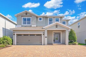 A two-story house with a garage, a front door, and a small porch. - The Encore Bliss - Nine Bedroom Apartment, Sleeps 18 (Kissimmee)