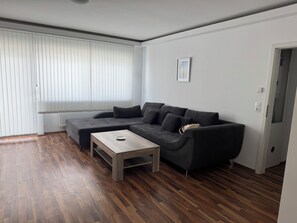Una sala moderna con un sofá seccional, una mesa de centro y un radiador.