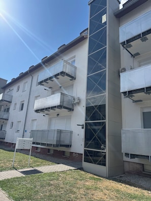 Un immeuble résidentiel à plusieurs étages, doté de balcons, de climatiseurs et de boîtes aux lettres.