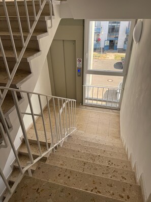 Una escalera con barandilla que lleva a una puerta con cerradura electrónica.