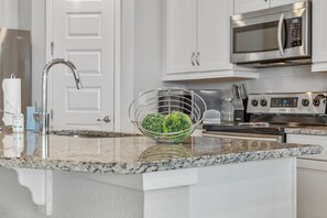 Una cocina con encimera de granito, electrodomésticos de acero inoxidable y una puerta blanca al fondo.