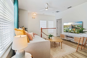 Ein modernes Wohnzimmer mit einer Couch, einem Couchtisch, einem Fernseher und einer Treppe, die zu einer weiteren Ebene führt.