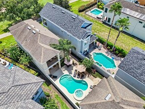 Ein Wohnhaus mit großem Swimmingpool, überdachter Terrasse und angelegtem Garten.