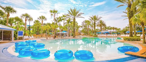 A swimming pool with multiple blue water slides, surrounded by palm trees and lounge chairs.
