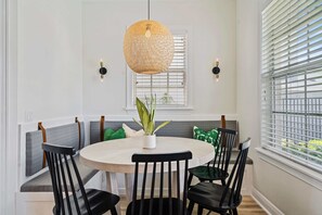 A dining area with a round table, black chairs, a woven pendant light, and a bench with cushions. - Summer Breeze - Four Bedroom Villa, Sleeps 8 (Kissimmee)