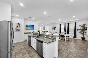 Eine moderne Küche mit Granit Arbeitsplatte, Edelstahlgeräten und einem Essbereich mit Tisch und Stühlen.