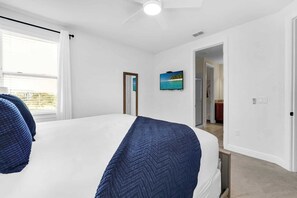 Ein Schlafzimmer mit einem Bett, einem Gemälde und Blick auf einen Balkon.