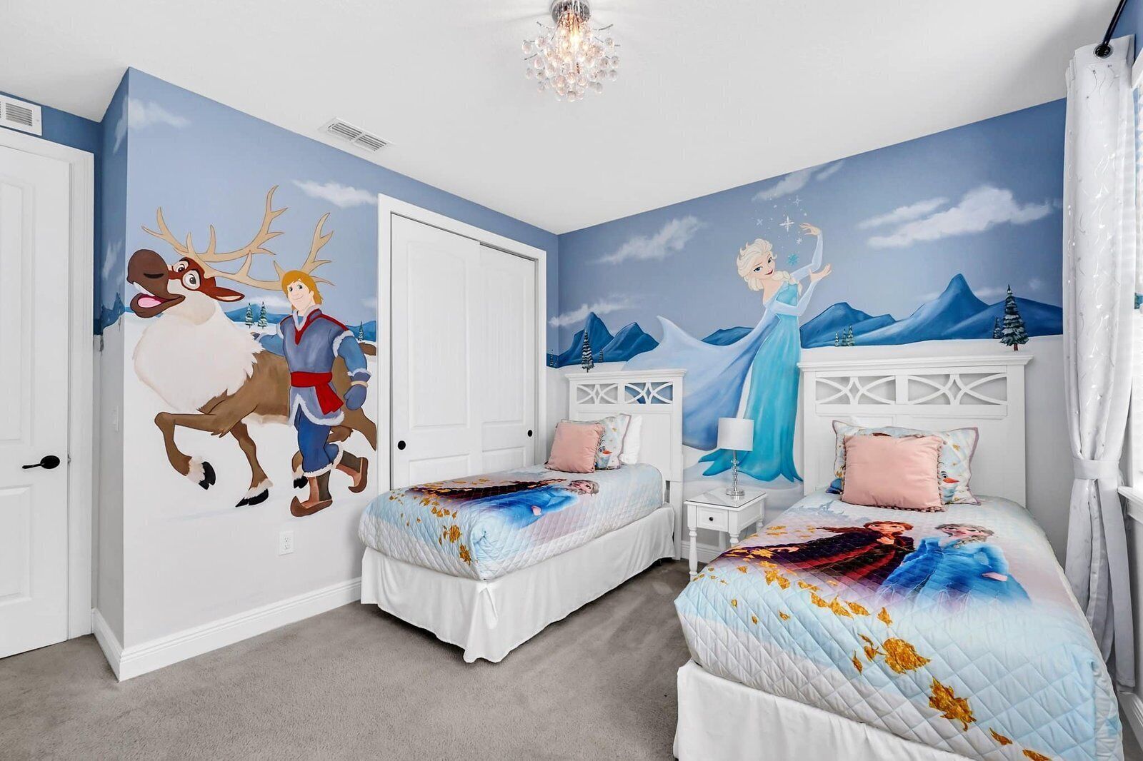 Ein Schlafzimmer mit zwei Betten, Wandgemälde und einer Chandelier.