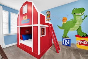 A child's playroom with a red barn-themed playhouse, a ladder, and a mural of a dinosaur and a dog. - Private south facing  Pool and Hot Tub-games room -ping pong-Close to disney (Lake Buena Vista)