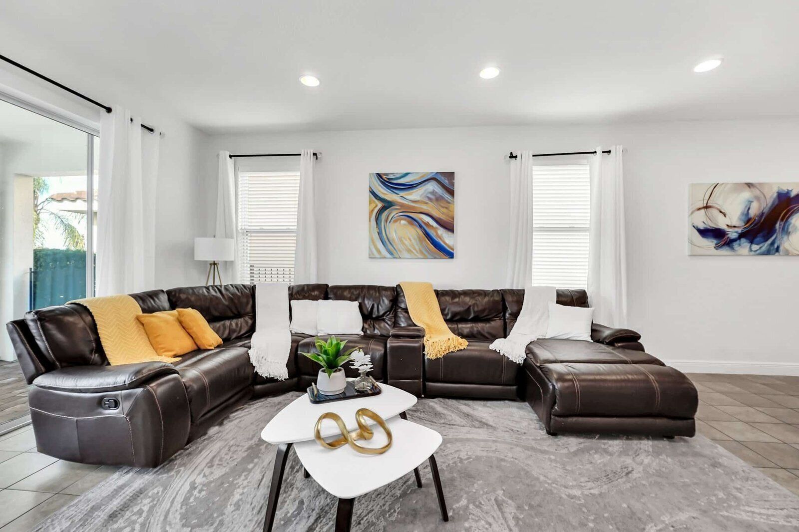 A modern living room with a sectional sofa, a coffee table, and abstract wall art.