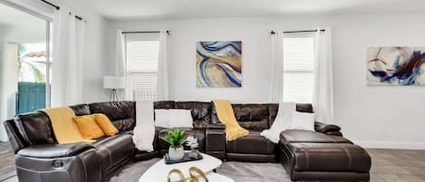A modern living room with a sectional sofa, a coffee table, and abstract wall art.