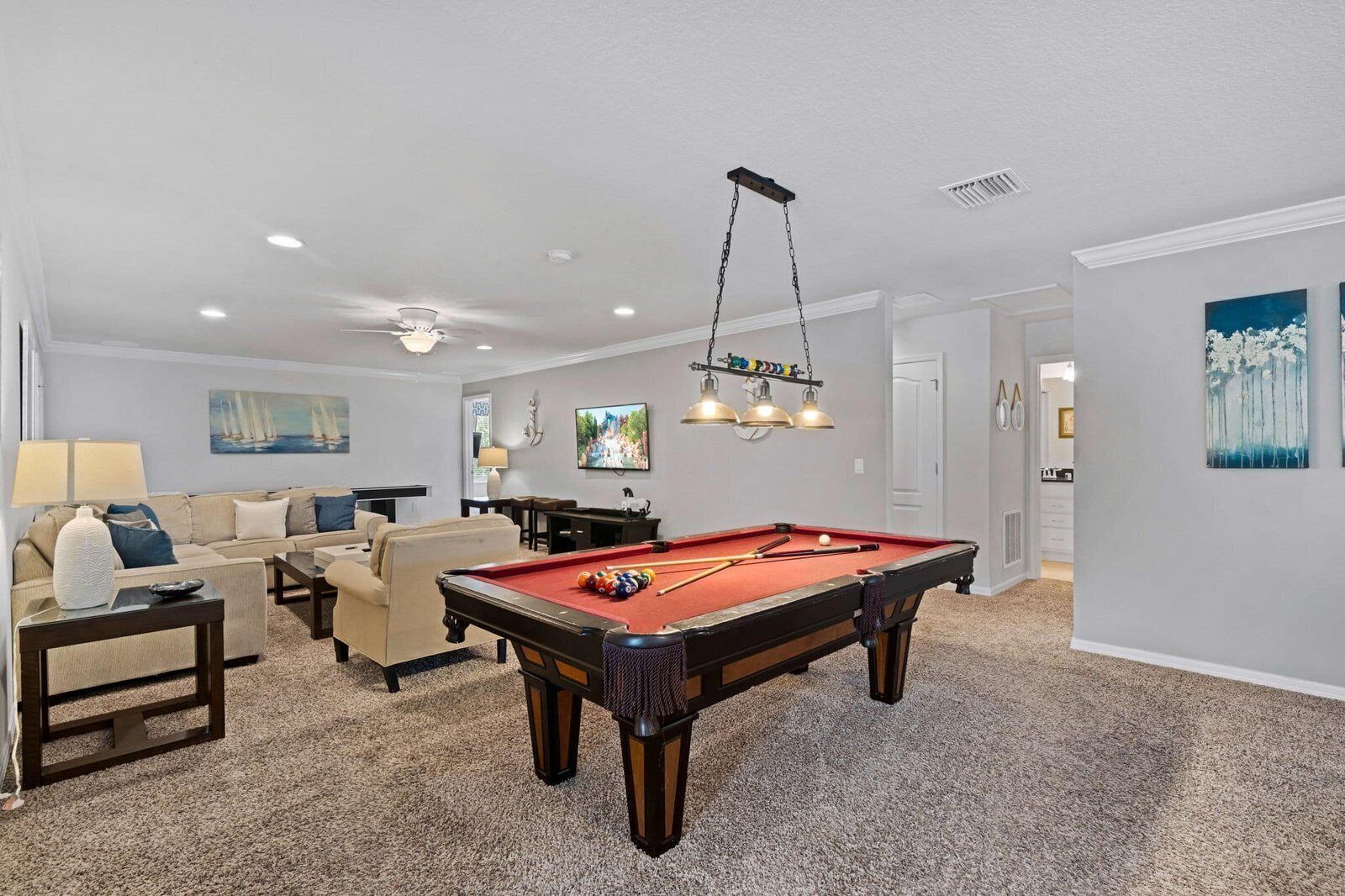 Un salon équipé d’une table de billard, d’un canapé, d’un téléviseur et d’un ventilateur de plafond.