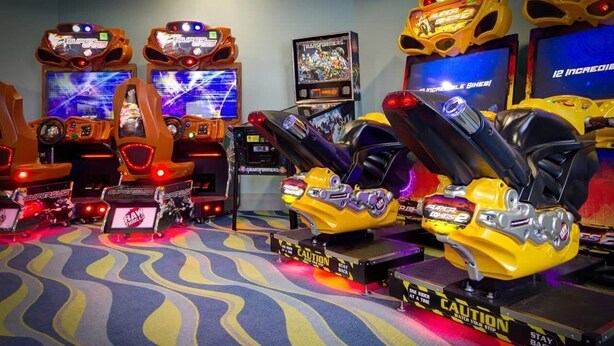 A gaming area with multiple arcade racing machines, including a yellow car-themed one, and a Transformers-themed machine. - Birdie Bungalow - Four Bedroom House, Sleeps 8 (Kissimmee)