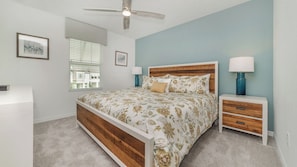 A bedroom with a bed, nightstands, a ceiling fan, and a window with blinds. - Coral Skies - Seven Bedroom Villa, Sleeps 16 (Kissimmee)