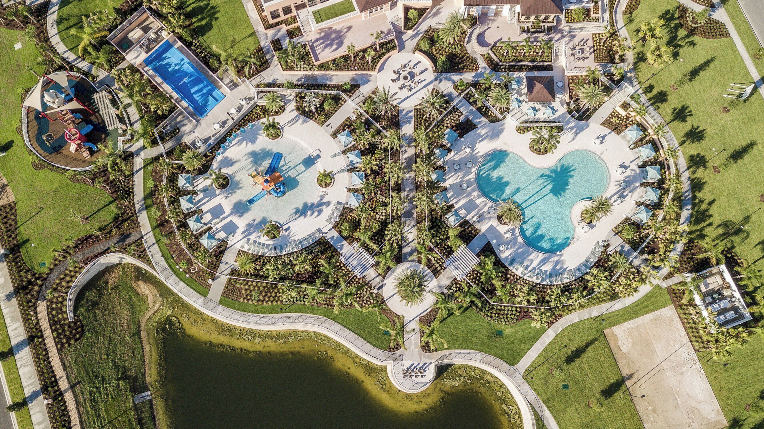 Ein Luftbild eines Resorts mit mehreren Schwimmbecken, Palmen und einem zentralen Wasserspielplatz.