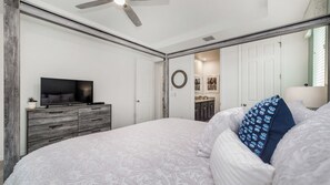 Un dormitorio con cama, cómoda, televisor y espejo.