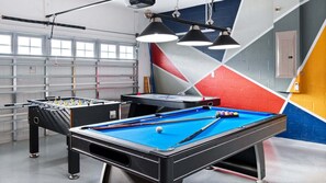 A pool table with a blue felt surface, a foosball table, and a billiards table in a room with geometric wall art and overhead lighting. - New Listing Sep 2026/Games Room/Cinema/Themed Bedrooms/Pool&Hot Tub (Kissimmee)