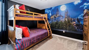 Een slaapkamer met stapelbed en een muurschildering van een kasteel en een volle maan.