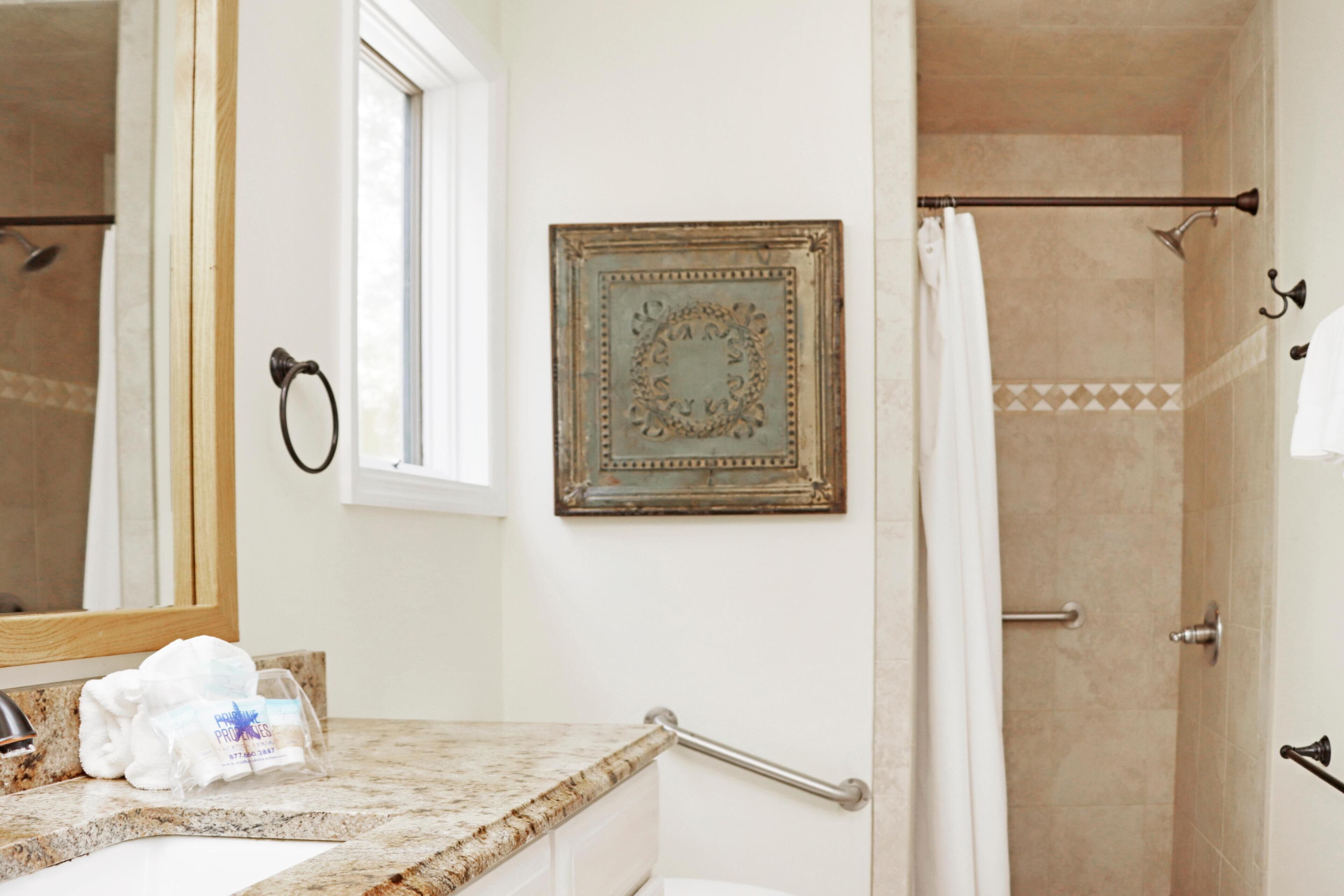 Une salle de bain équipée d’un meuble-lavabo, d’une douche, d’un porte-serviettes et d’un tableau encadré au mur.