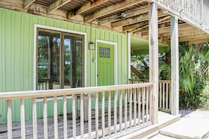 A green building with a wooden porch and a door with a window. - Hidden Palms (Port St. Joe)