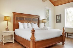 A neatly made bed with a wooden headboard, two bedside tables with lamps, and a window with blinds. - Hidden Palms (Port St. Joe)