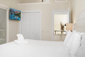A hotel room with a bed, a set of white doors, a painting, and a lamp. - Hidden Palms (Port St. Joe)