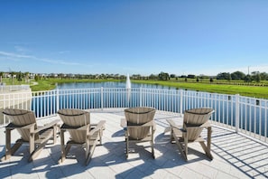 Ein Poolbereich mit Adirondack-Stühlen und Blick auf einen See.