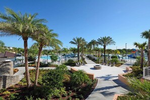 A resort with a pool area, palm trees, and a stone building. - Island Vibes - Five Bedroom House, Sleeps 12 (Kissimmee)