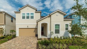 A two-story residential building with a garage, a front entrance, and a landscaped front yard. - Maison Calme - Five Bedroom Villa, Sleeps 13 (Kissimmee)