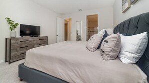 A bedroom with a bed, a television on a wooden dresser, and a door leading to another room. - New Listing! 6 miles Disney/Private Pool and Spa/Flowrider/Teen hangout (Kissimmee)