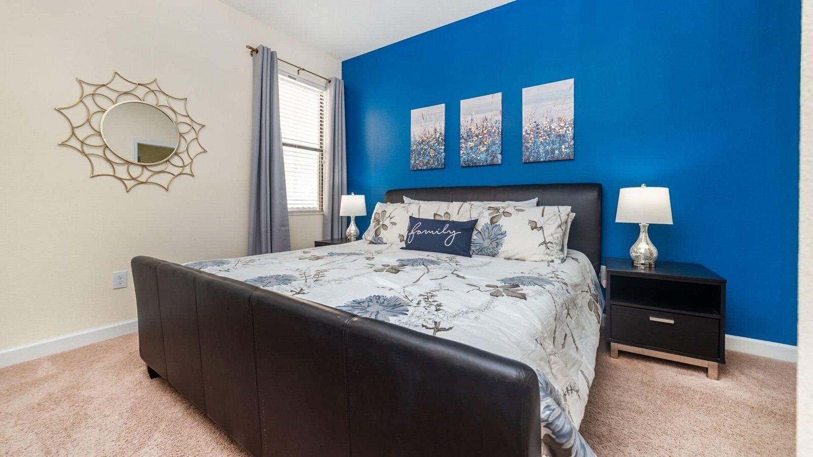 A bedroom with a bed, nightstands, a mirror, and artwork on the wall.