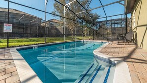 A clear swimming pool with a tiled edge, surrounded by a covered area with chairs. - Mickeys Hideout - Four Bedroom House, Sleeps 8 (Kissimmee)
