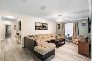 Ein Wohnzimmer mit Ecksofa, Couchtisch und Fernseher.