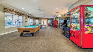 A pool table, claw machines, and a billiards table in a room with carpeted flooring and large windows. - Windsor Hills Resort/2 Miles Disney/Private Pool and Hot Tub/Games Room/FreeWifi (Kissimmee)