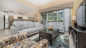 A modern living room with a sofa, a coffee table, and a television. - Orange Blossom Villa (Kissimmee)